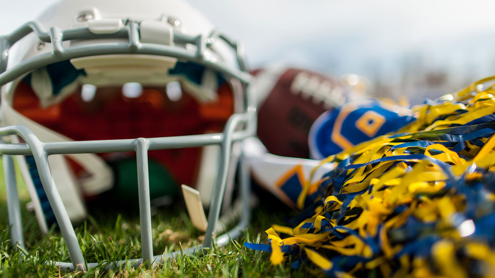 This picture is of a football helmet and pom poms to promote the tailgate event.